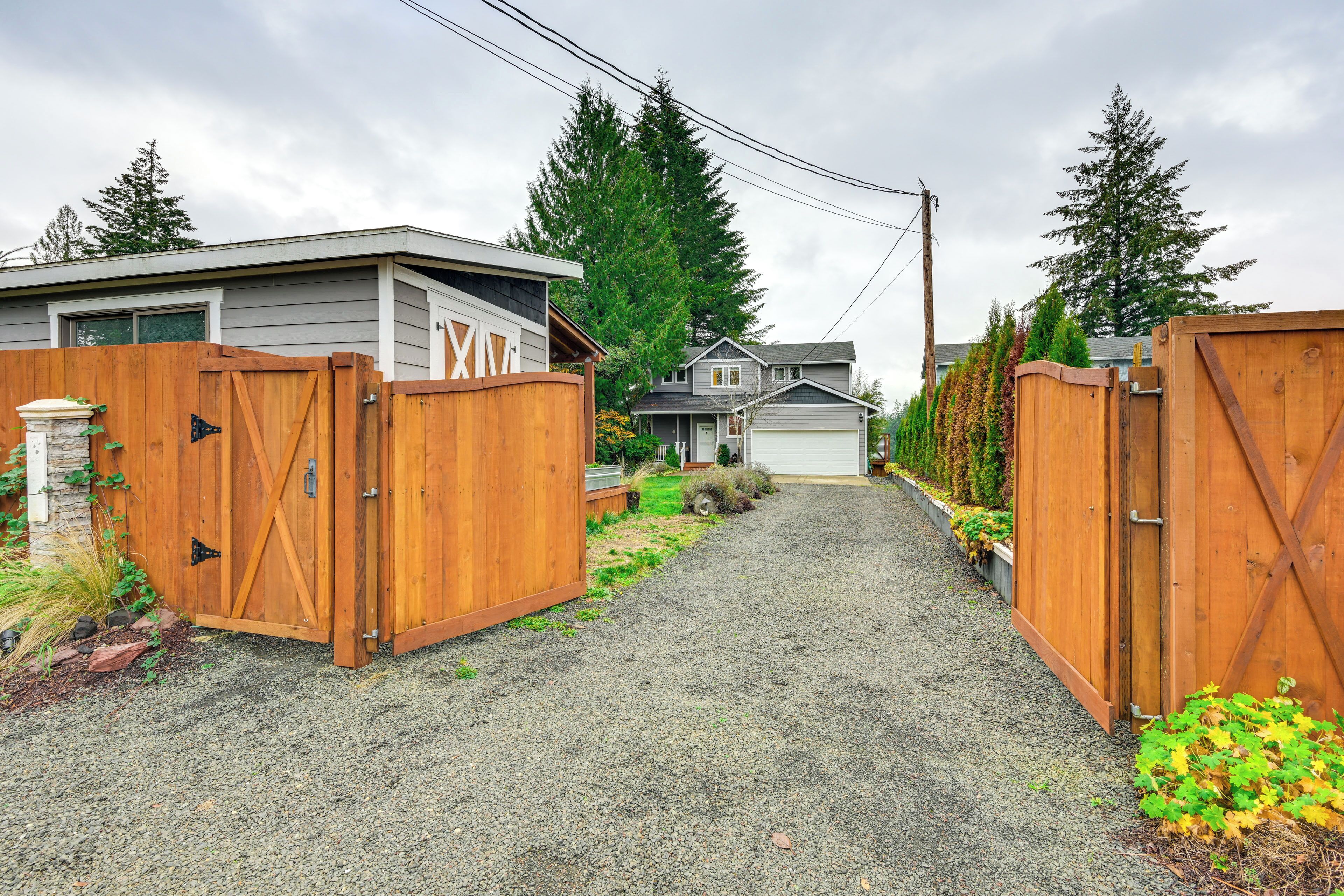 A gravel driveway leading to a house with a wooden gate.