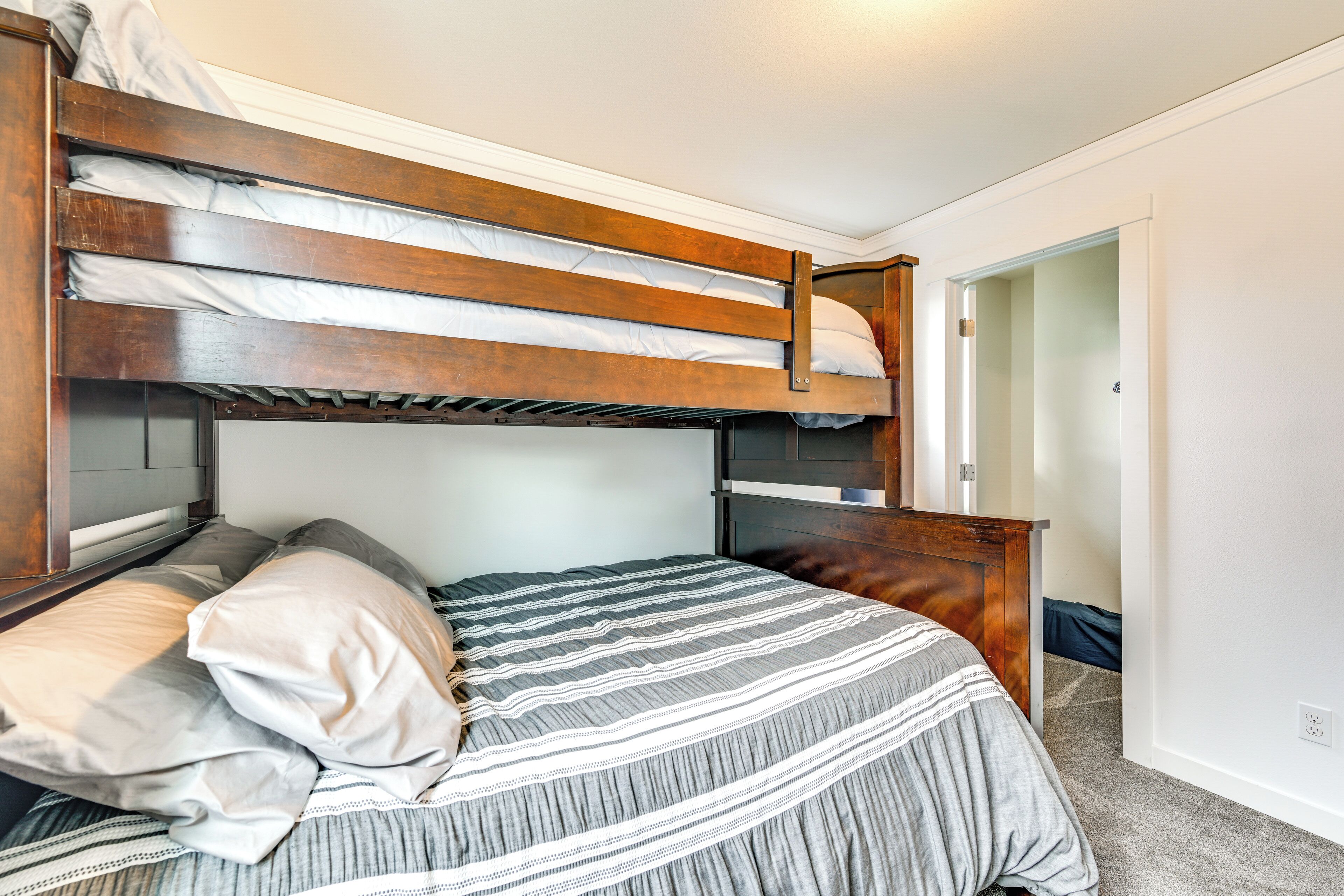 Un lit superposé avec une couvre-lit et des oreillers à rayures, une tête de lit en bois et une table de chevet.