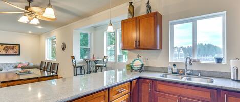 A kitchen with wooden cabinets, a granite countertop, a built-in sink, and a ceiling fan.