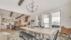 A spacious kitchen with a large dining table, modern appliances, and large windows offering a view of the outside.