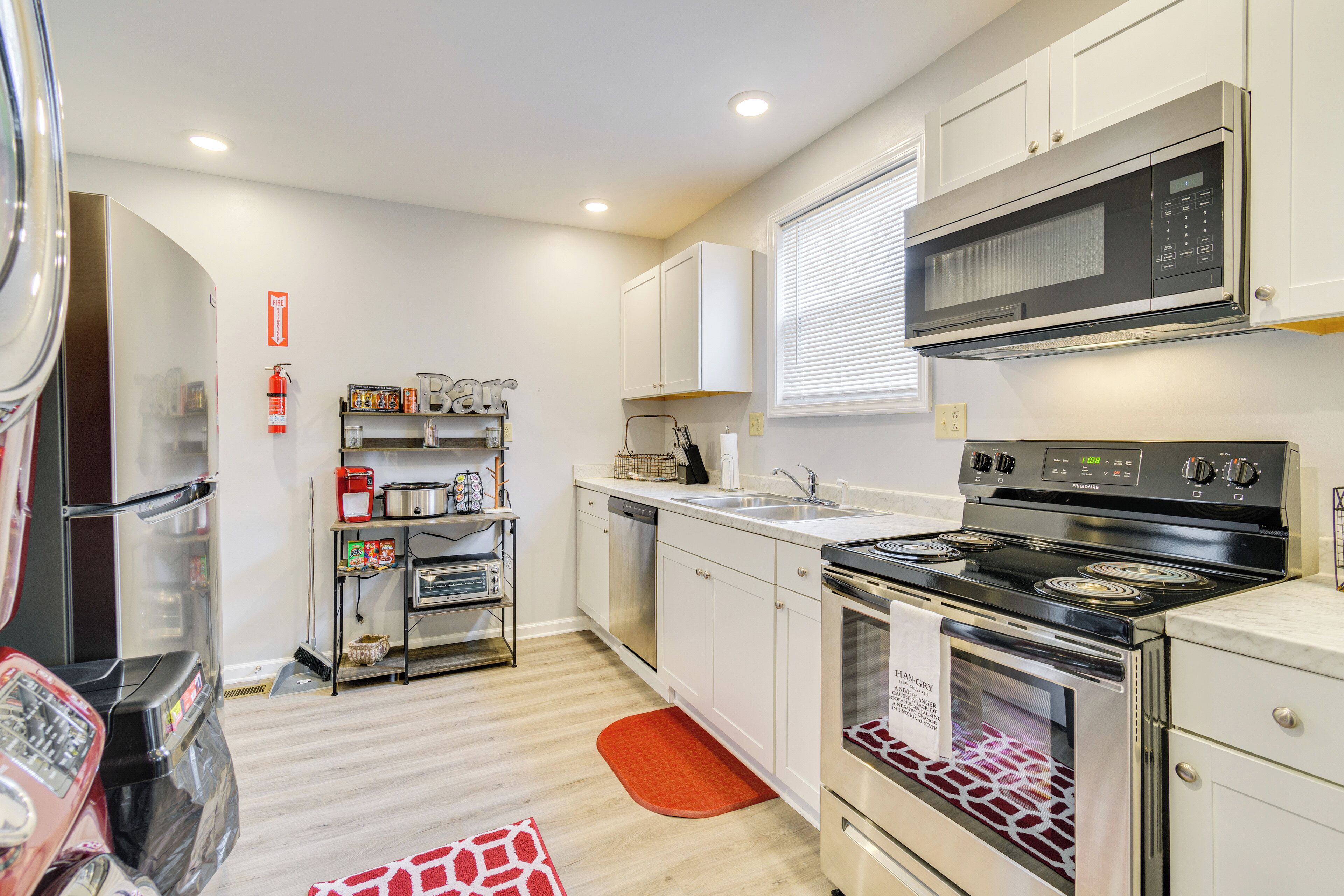 Una cocina moderna con electrodomésticos de acero inoxidable, armarios blancos y una alfombra roja.