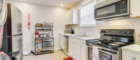 Una cocina moderna con electrodomésticos de acero inoxidable, armarios blancos y una alfombra roja.
