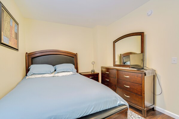 A bedroom with a bed, a dresser, a nightstand, and a mirror.