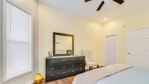 A bedroom with a bed, dresser, chair, and a door.