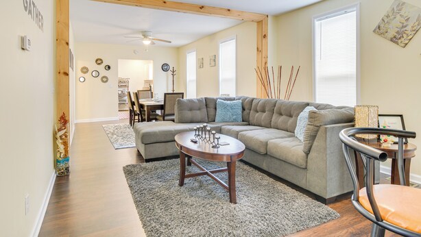 A living room with a sectional sofa, a round coffee table, and a dining area in the background.