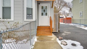 A residential property with a white front door, wooden steps, and a chain-link fence.
