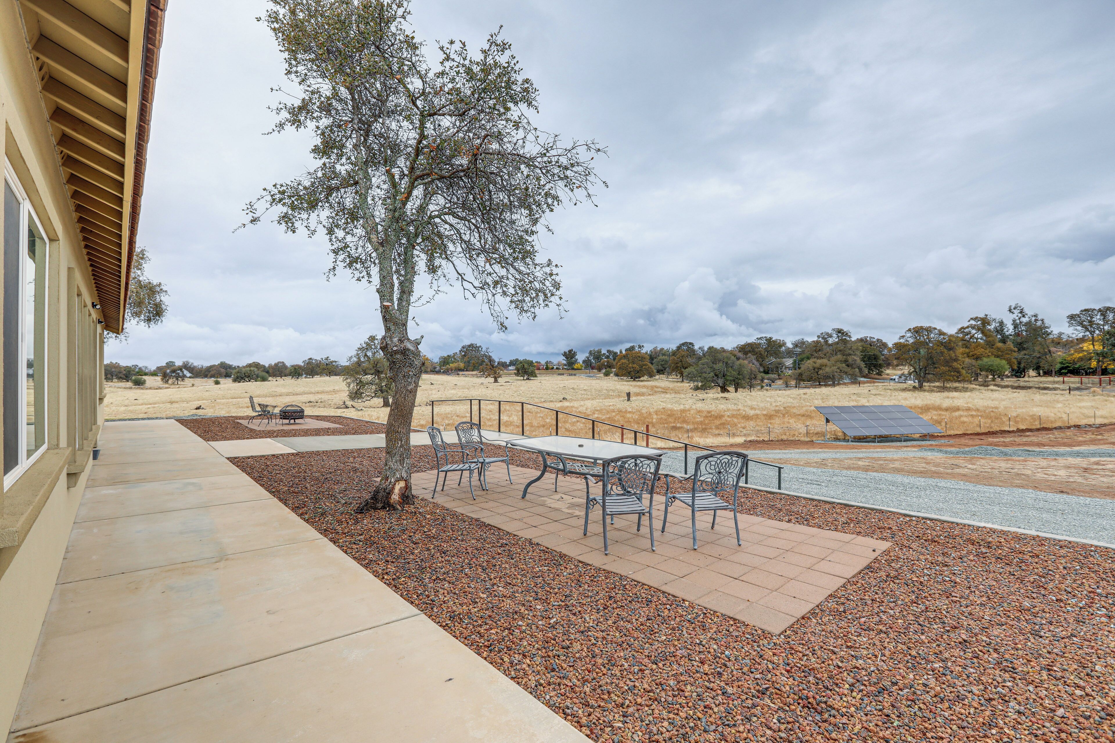 Un patio con mesa y sillas, un árbol y un panel solar.