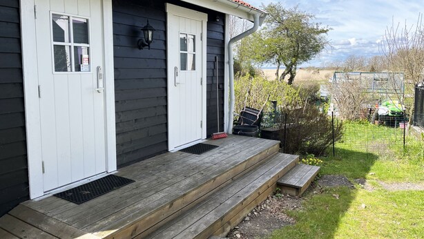 Una casa de exterior oscuro, con puertas blancas y un porche de madera.