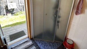Una habitación con puerta de vidrio corredera que da a un patio, piso de baldosas y un bote de basura rojo.