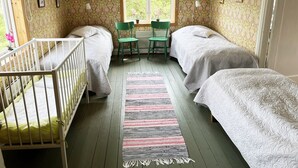 A room with two beds, a crib, a window with a view of greenery, and a patterned rug. - Cozy red cottage in the countryside outside Vimmerby I SE05038 (Gullringen)
