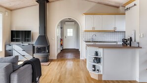 A modern kitchen with white cabinets, a wooden ceiling, and a built-in stove.