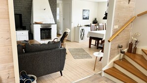 Una sala de estar moderna con chimenea, un comedor y una escalera.