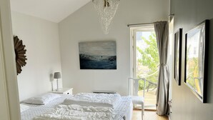 Un dormitorio con una cama grande, un cuadro, una lámpara de araña y vistas al exterior.