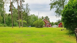 Ein grünes Feld mit einem roten Stall und einem weißen Gebäude im Hintergrund.