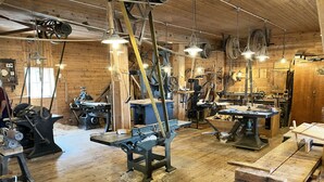 A workshop with wooden walls, various woodworking tools, and machinery.