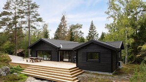 A cabin with two separate sections, each with a sliding glass door and a small porch. There is a wooden deck leading to the cabin, and a picnic table is visible.