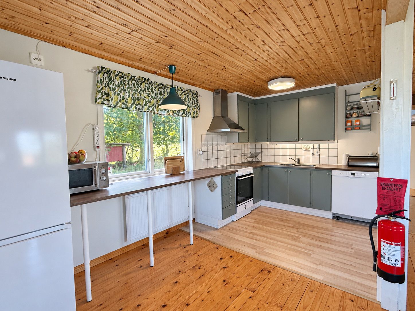 Une cuisine avec un plancher en bois, un four à micro-ondes, une cuisinière et un lave-vaisselle.