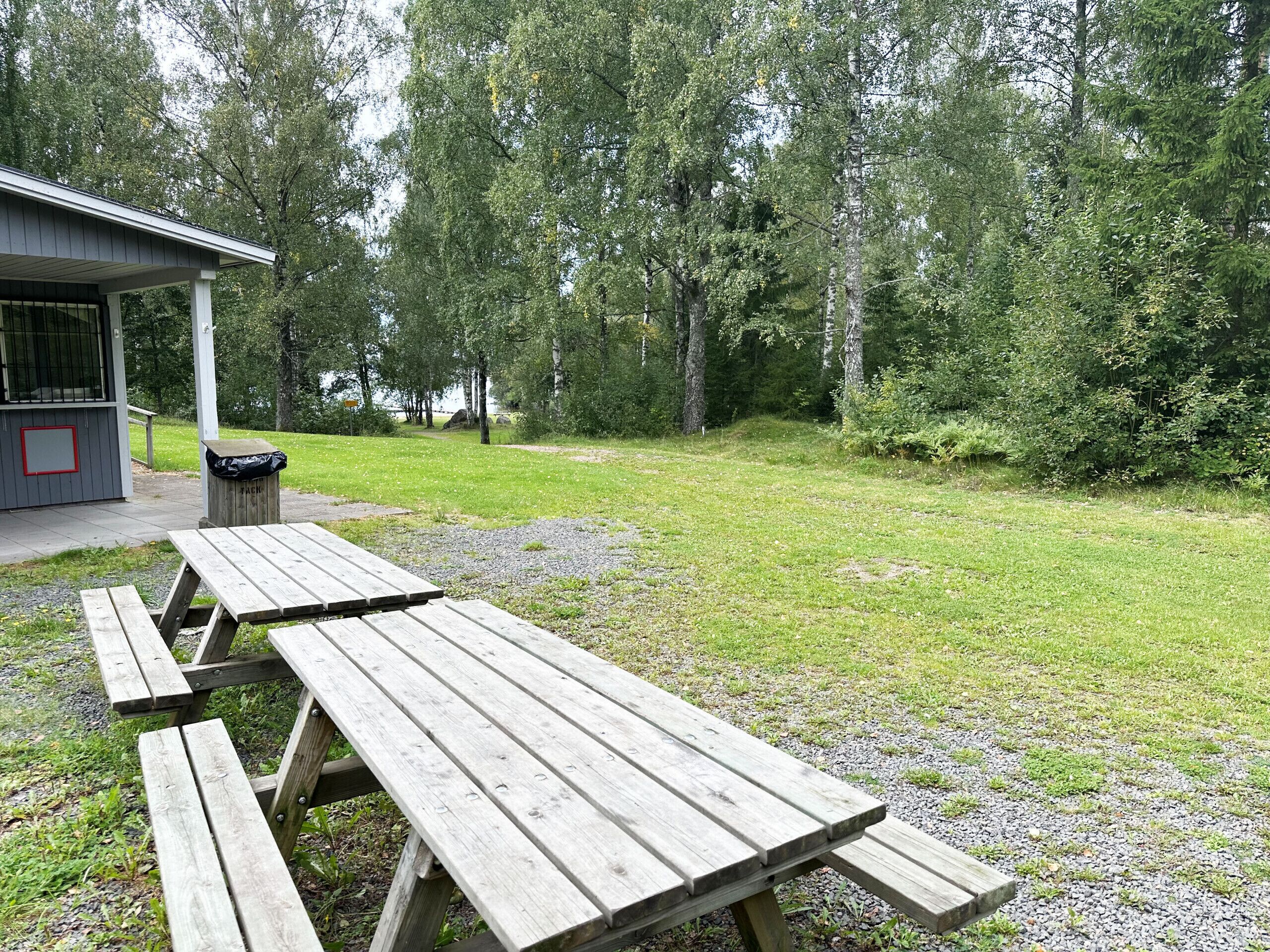 Une table de pique-nique dans un parc, avec un bâtiment en arrière-plan.