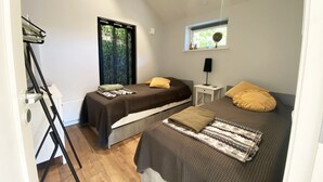 Ein Schlafzimmer mit zwei Betten, einem Fenster, einem Nachttisch mit Lampe und einem Deckenventilator.