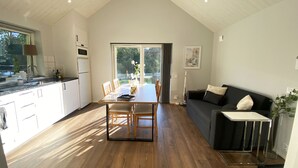 Eine moderne Küche mit Holzboden, einem Esstisch und einem schwarzen Sofa.