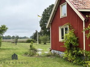 A red building with a window and a flagpole with a flag.