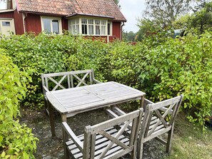 A wooden table and chairs in a garden with a red house in the background. - Nice cottage located close to a bay in Skäppevik I SE05046 (Bergkvara)