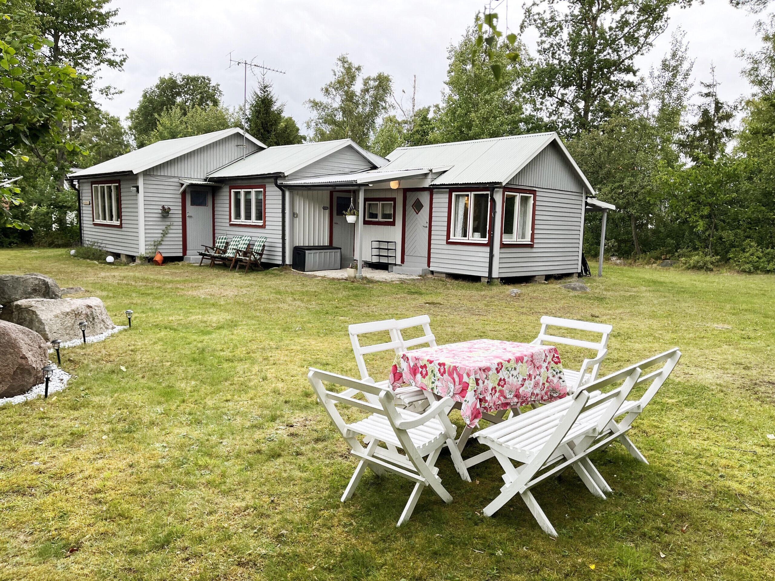 Une cabane à deux étages avec un porche, une table et des chaises, et une pelouse.