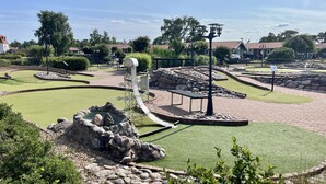 Un campo da minigolf con un percorso tortuoso, un ostacolo d'acqua e un gazebo.