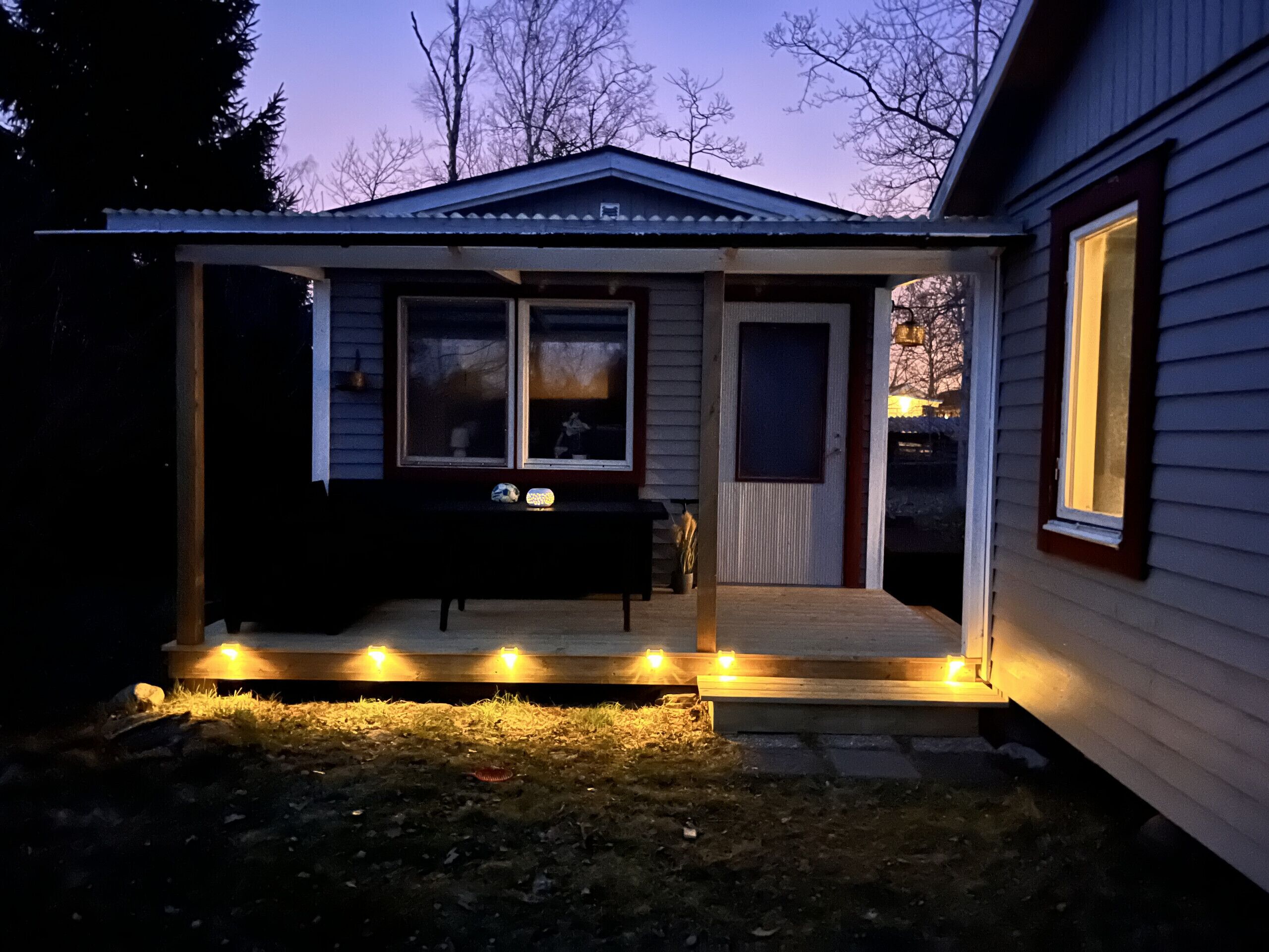 A covered porch with a bench and a table, a door, and a window.
