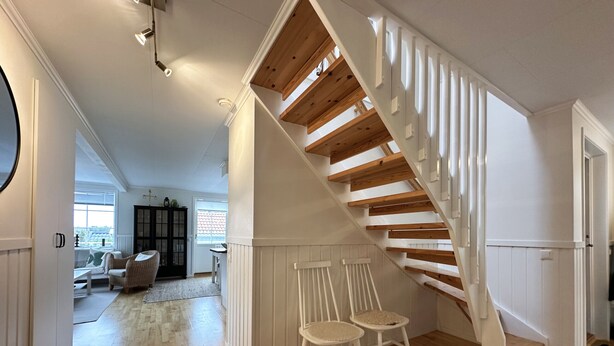 Una escalera de madera con barandillas blancas que lleva a un piso superior.