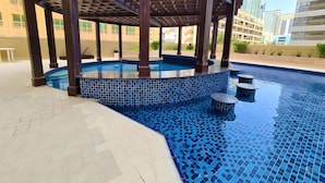 Piscina com borda em azulejo e estrutura de pérgula de madeira.