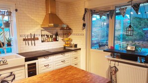 Una cocina con mesa de madera, armarios blancos, pared de ladrillo y ventana con vistas.