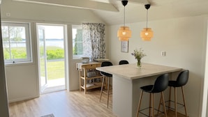 A modern kitchen with a wooden island, black bar stools, and a view of the outdoors.
