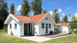 A two-story white house with a red-tiled roof, a covered porch, and a small garden area.