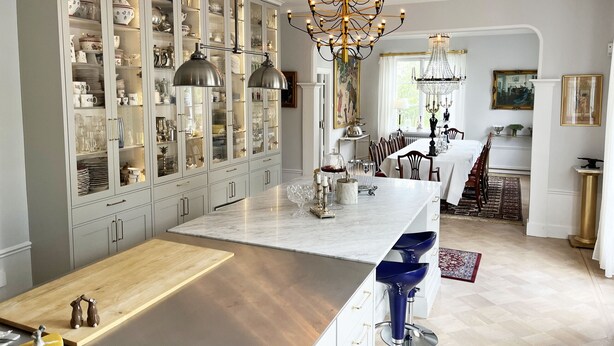 A spacious kitchen with a marble island, a dining area with a chandelier, and a large cabinet filled with dishes. - Magnificent, spacious villa located in the middle of Vimmerby in SE05056 (Vimmerby)