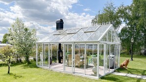 A glass greenhouse with a roof, a table with chairs, and a statue. - Magnificent, spacious villa located in the middle of Vimmerby in SE05056 (Vimmerby)