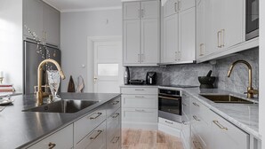 A modern kitchen with grey cabinets, stainless steel appliances, and gold handles. - Magnificent, spacious villa located in the middle of Vimmerby in SE05056 (Vimmerby)