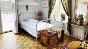 A bedroom with a bed, a chest of drawers, a dresser, a chandelier, a window with curtains, and a mirror. - Magnificent, spacious villa located in the middle of Vimmerby in SE05056 (Vimmerby)