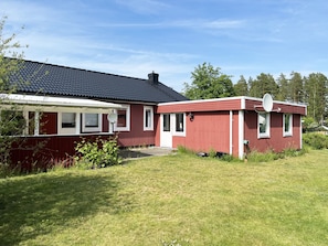 Punainen puutalo, jossa on satelliittiantenni, savupiippu ja pieni siihen liittyvä lisärakennus.