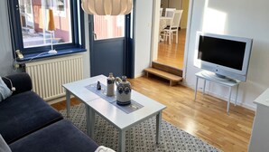 A modern living room with a sofa, a table with decorative items, a TV, and a view of the outside. - Large and spacious villa located in Storebro close to a nice swimming area | SE05059 (Storebro)