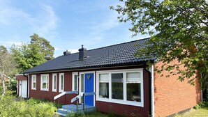 A red brick house with a blue door and white windows, a chimney, and a small porch with steps. - Large and spacious villa located in Storebro close to a nice swimming area | SE05059 (Storebro)