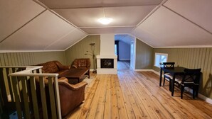 Ein Schlafzimmer im Loft-Stil mit Holzboden, Kamin, Sofa und Esstisch.