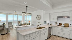 A modern kitchen with white cabinetry, a large island, and a view of the ocean. - Perdido Dunes Tower 7W by Liquid Life (Orange Beach)