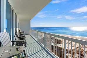 A balcony with Adirondack chairs overlooking a beach.