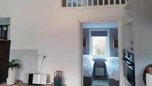 Une pièce avec un lit, un radiateur, une fenêtre et une plante.