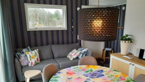 Un salon moderne avec un canapé gris, une nappe à motifs floraux et une grande fenêtre.