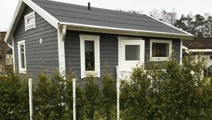 Une maison de plain-pied à l’extérieur gris foncé, avec des moulures blanches et un toit à pignon.
