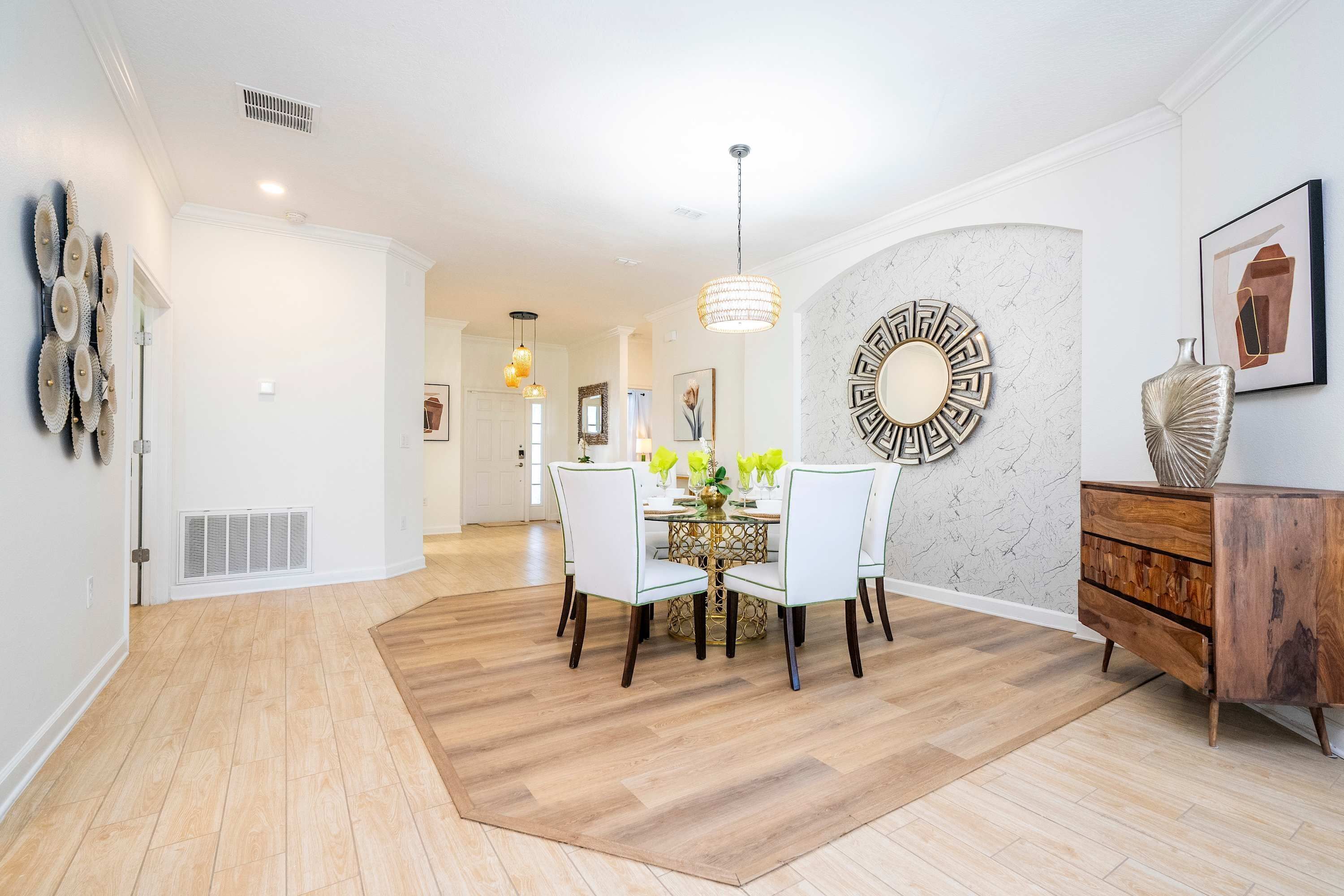 A modern dining area with a round table, white chairs, and a chandelier.