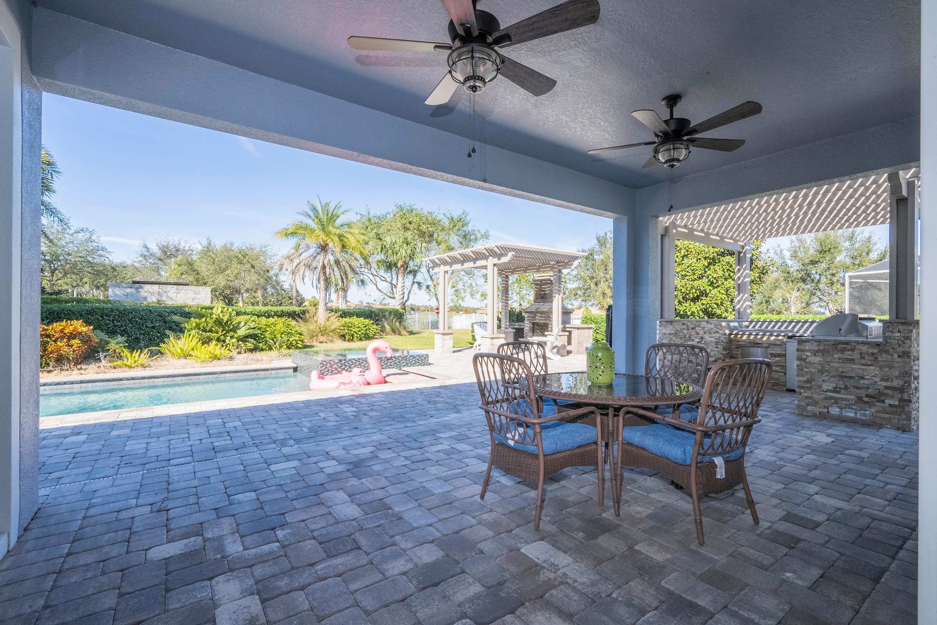 An outdoor patio with a pool, chairs, and ceiling fans.