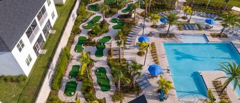An aerial view of a resort with a pool, multiple golf courses, and a building with balconies.